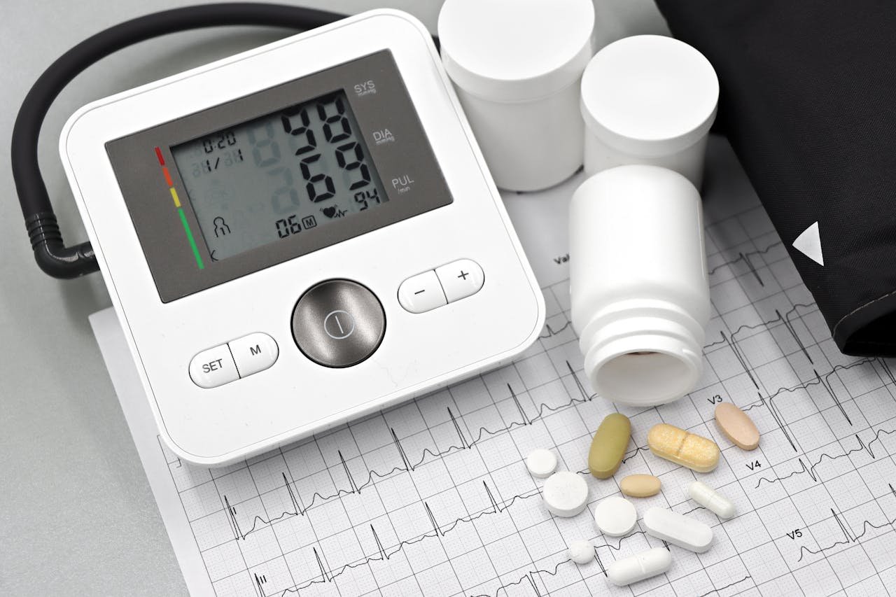 Blood pressure monitor with pills on ECG sheet, essential for heart health management.